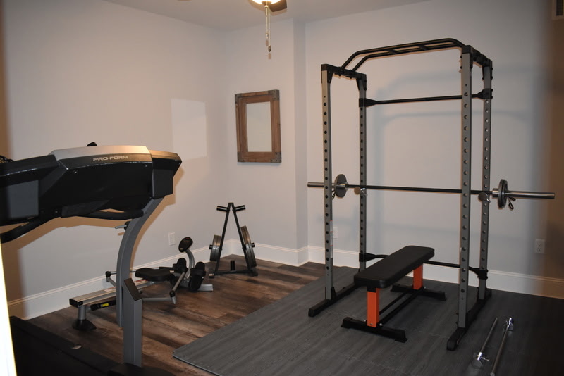 Finished basement home gym with power rack and dark flooring