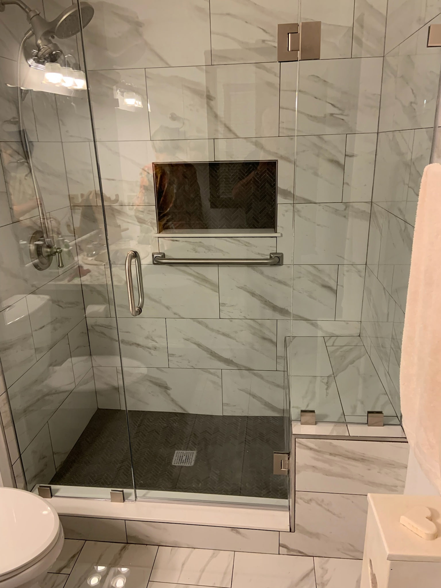 Finished basement bathroom marble tile frameless glass shower with bench