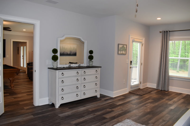 Finished basement bedroom with dark hardwood floors and dresser