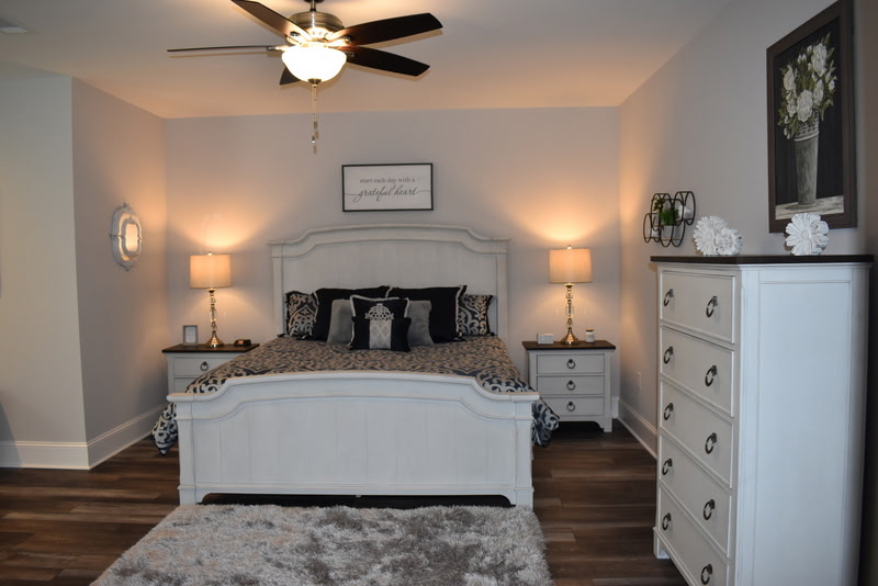 Finished basement bedroom suite with white furniture and ceiling fan