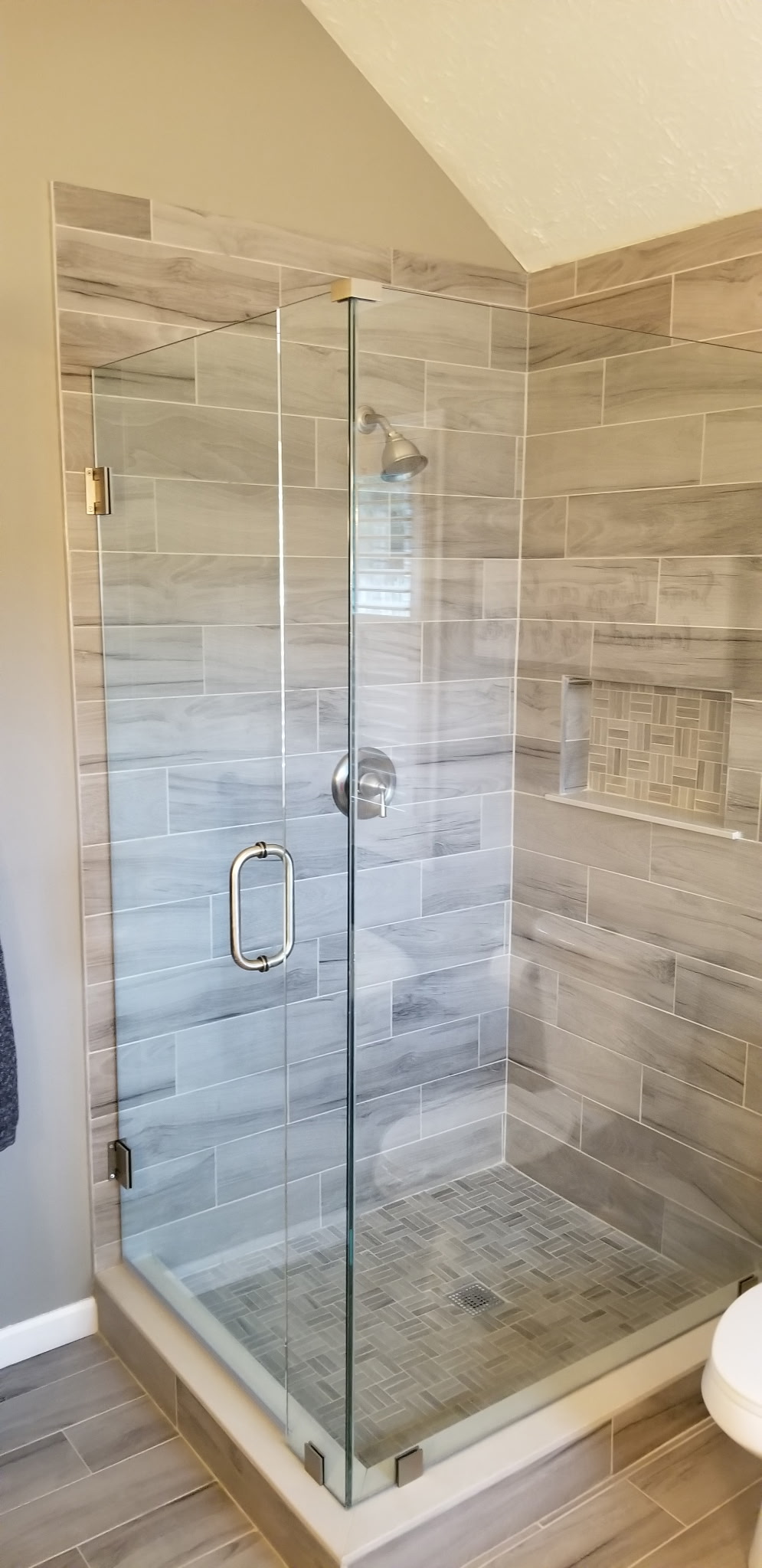 Glass shower with wood-look tile and basket weave floor tile