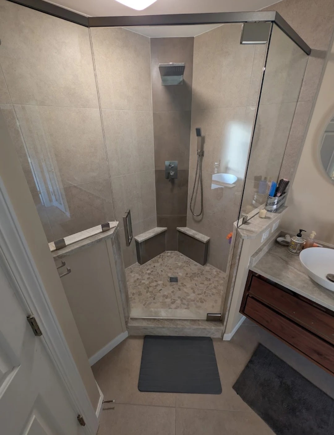 Corner glass shower with large format tile, pebble floor and rain head