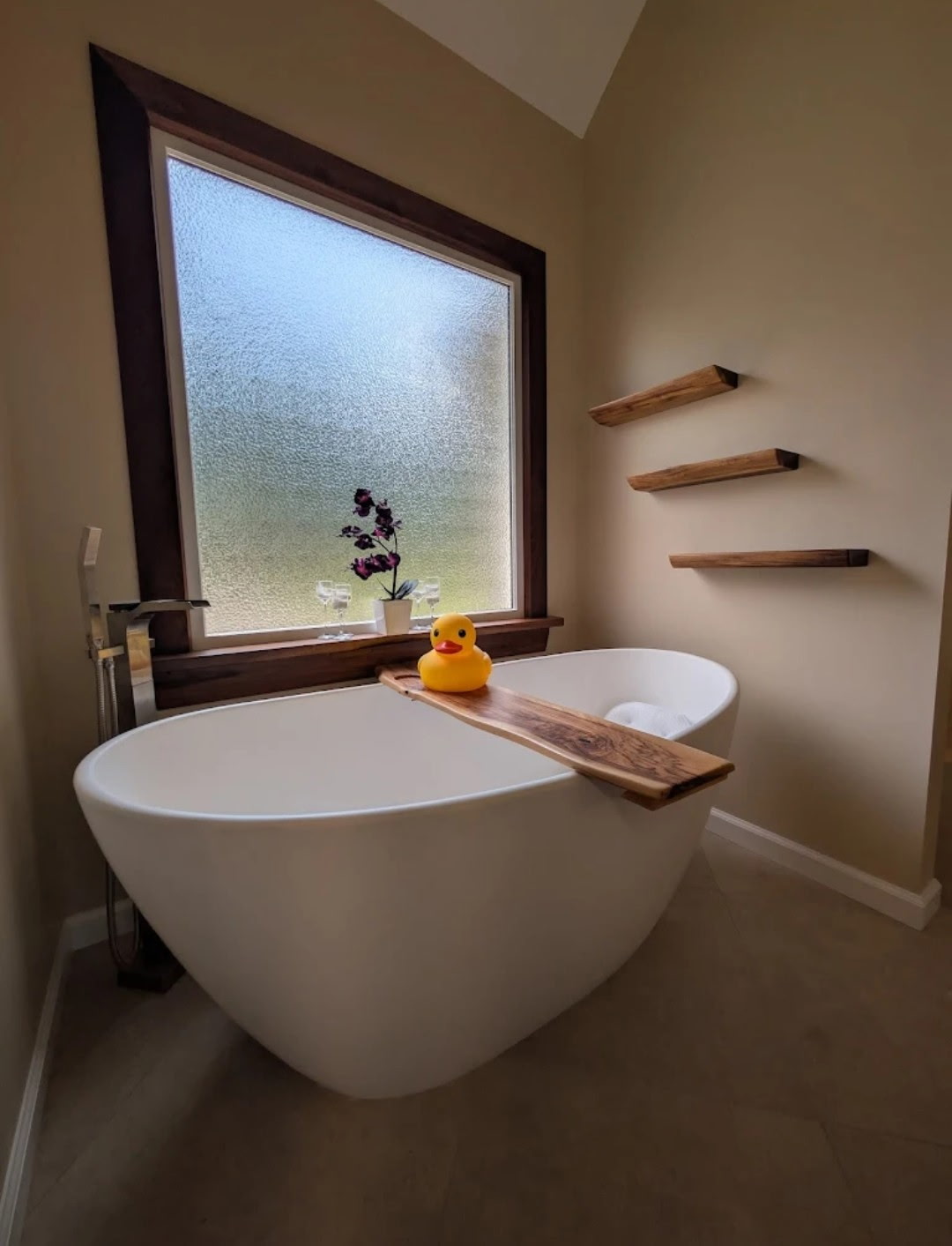 Freestanding soaking tub with wood tray and live edge floating shelves