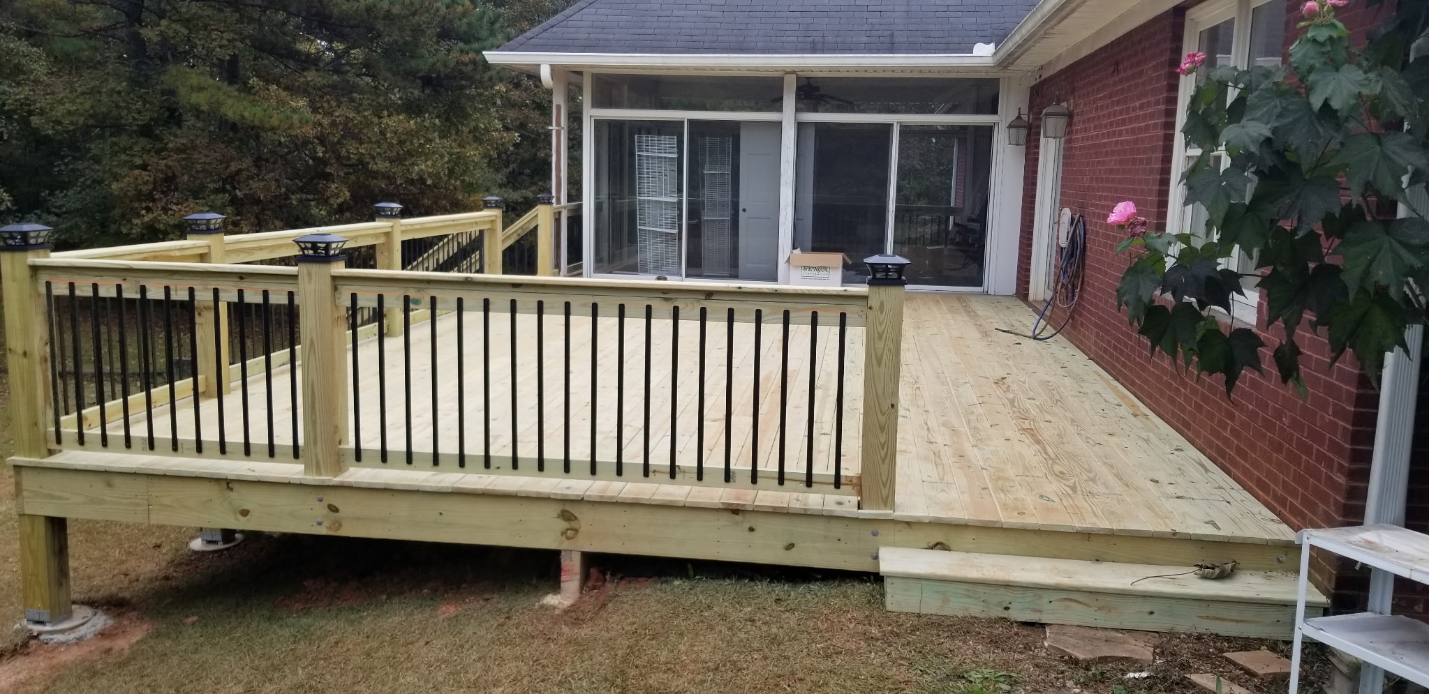 New pressure-treated deck with black metal balusters and solar post caps