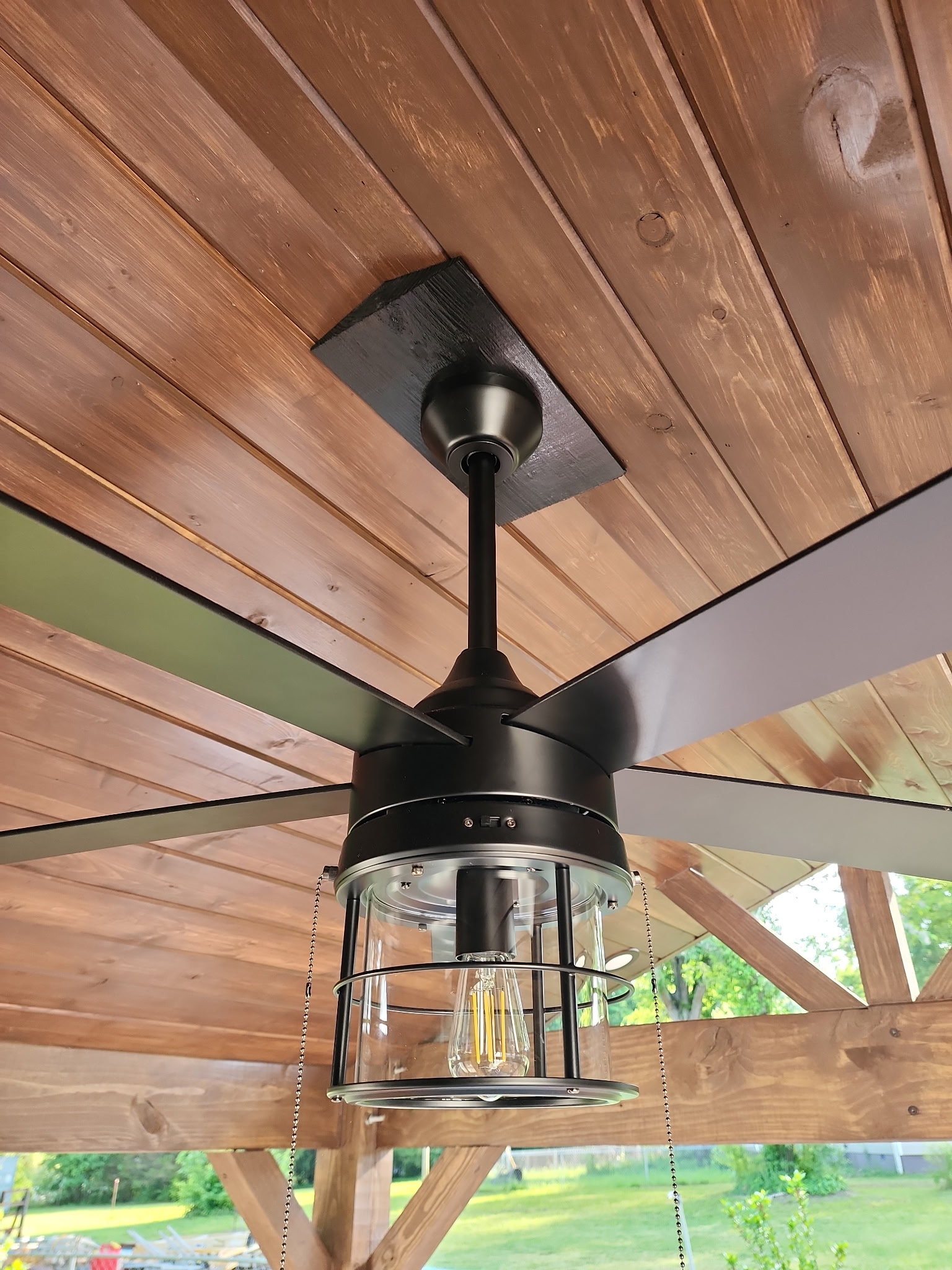 Pergola ceiling detail with black ceiling fan and Edison bulb light