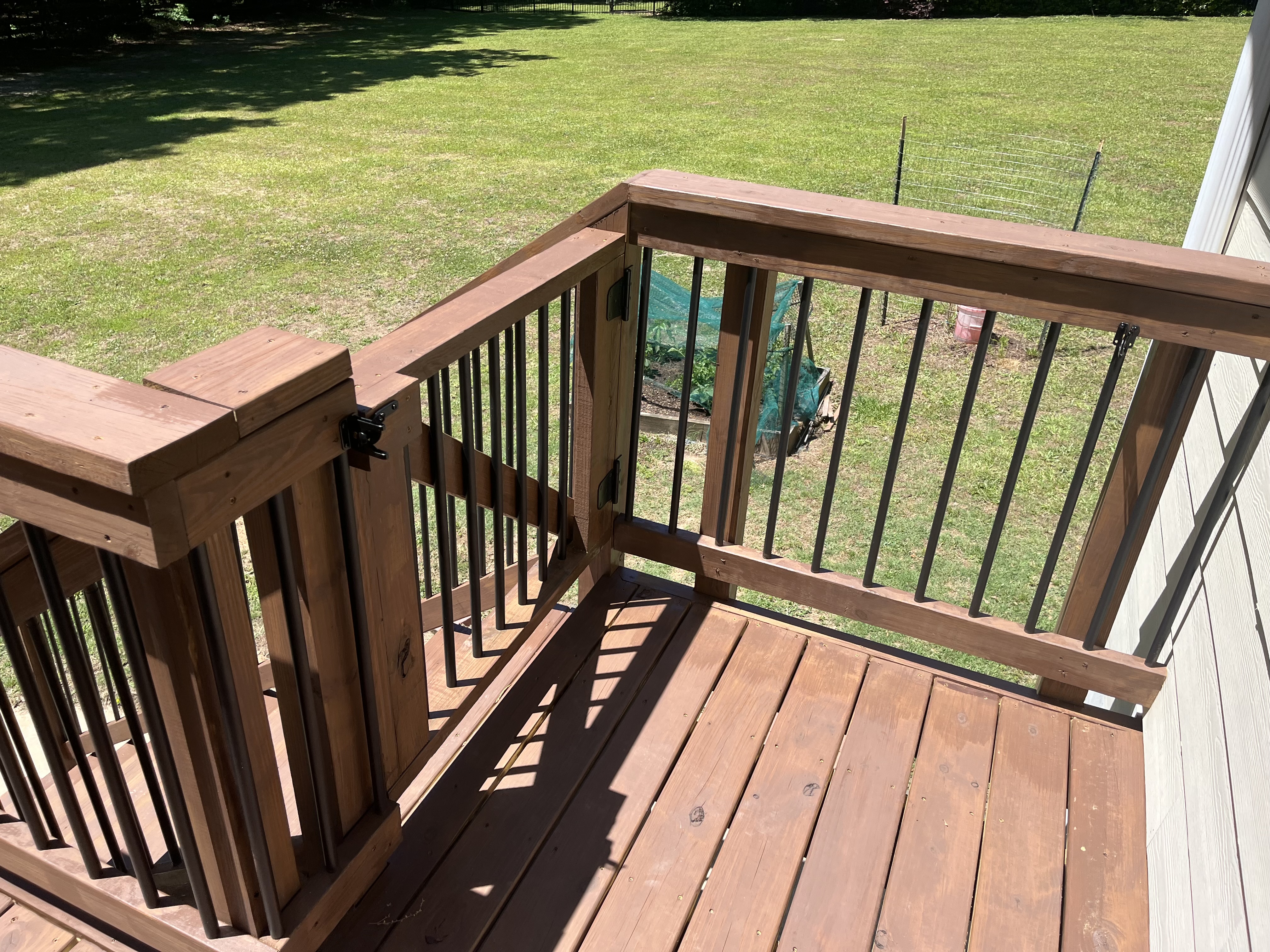 Deck with built-in gate and black metal balusters overlooking yard