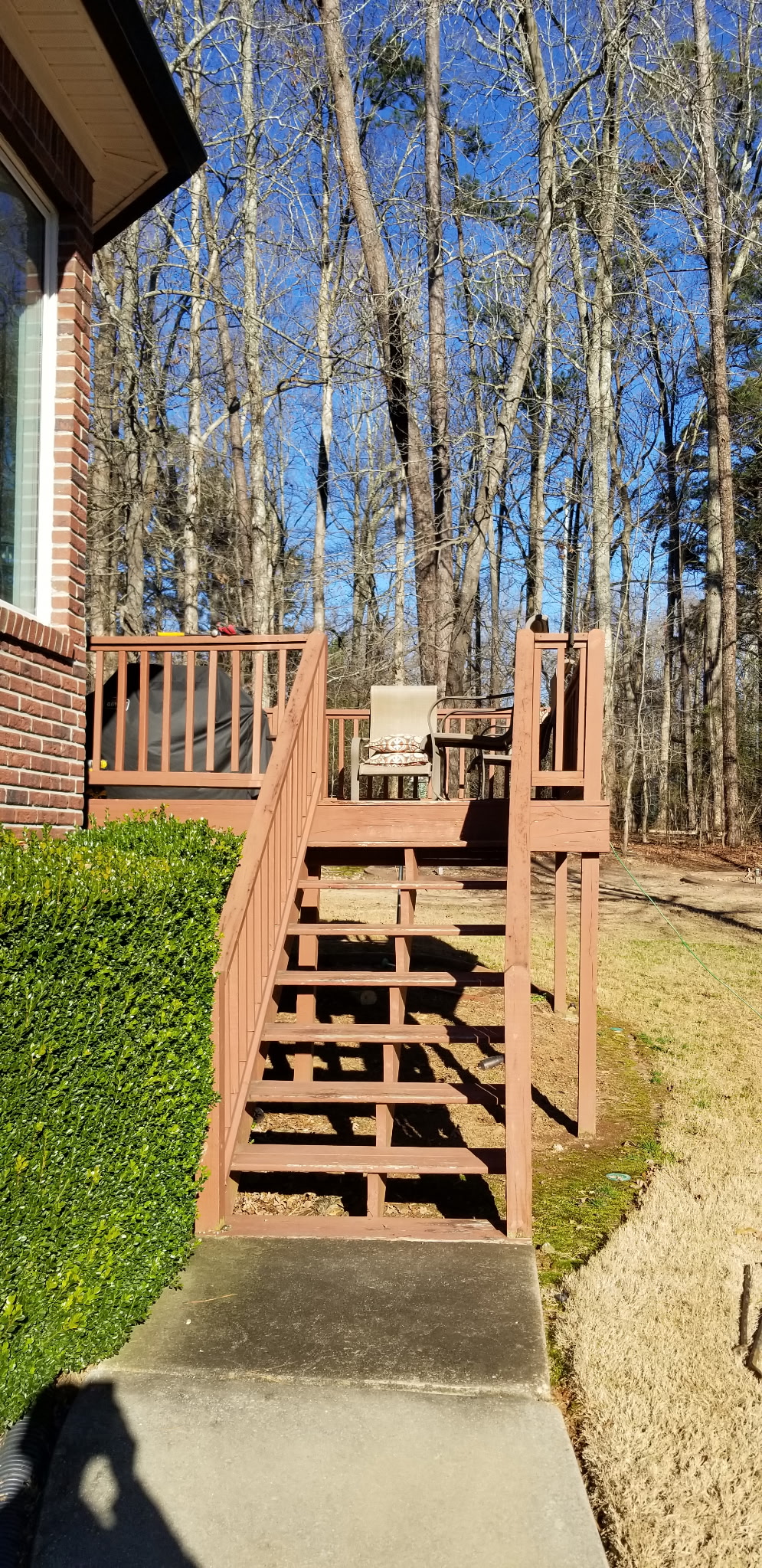 Stained deck with stairs and brick home backdrop