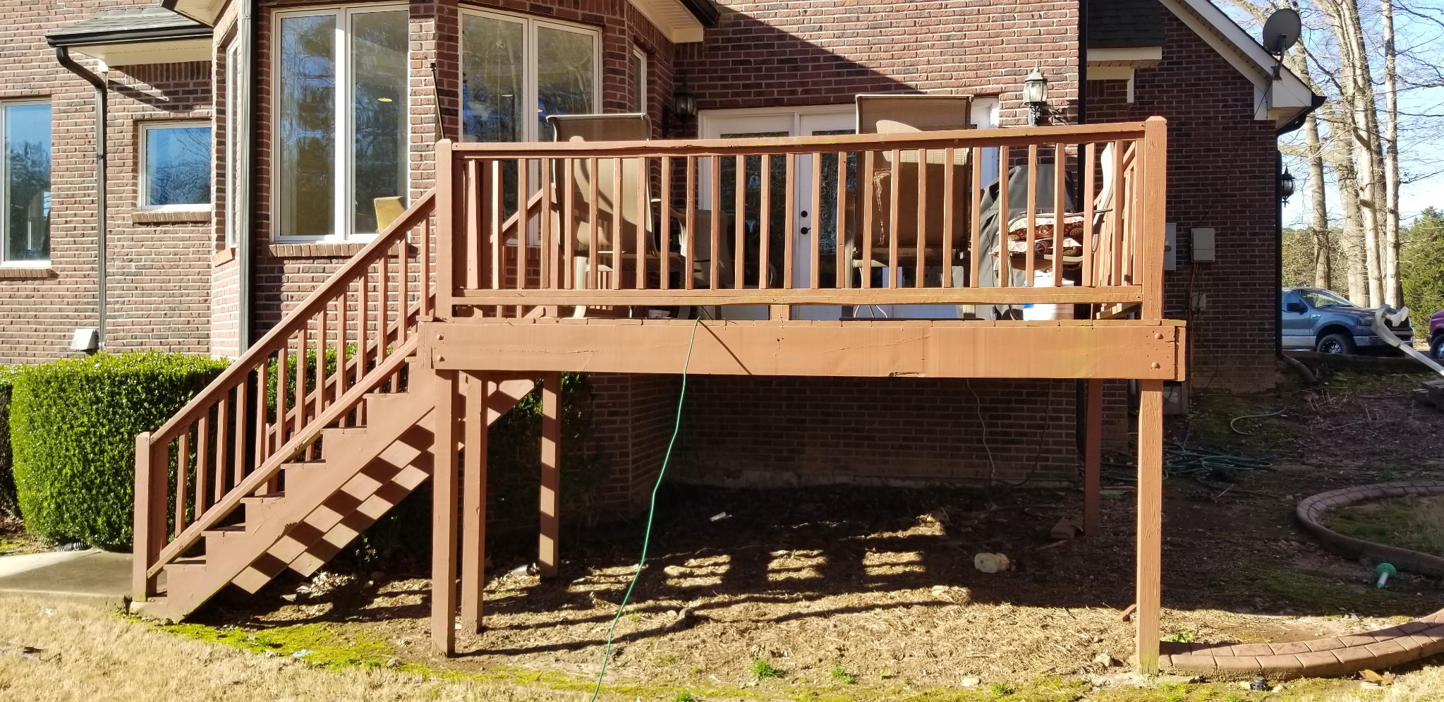 Elevated stained deck with full staircase and brick home