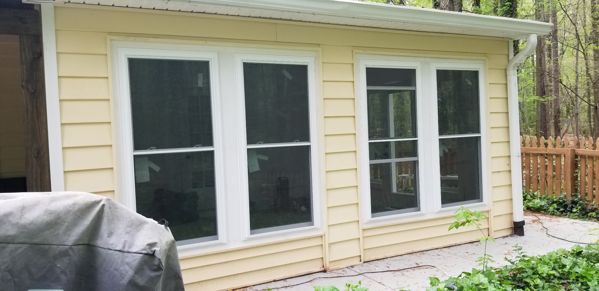 Four new white replacement windows on yellow home exterior