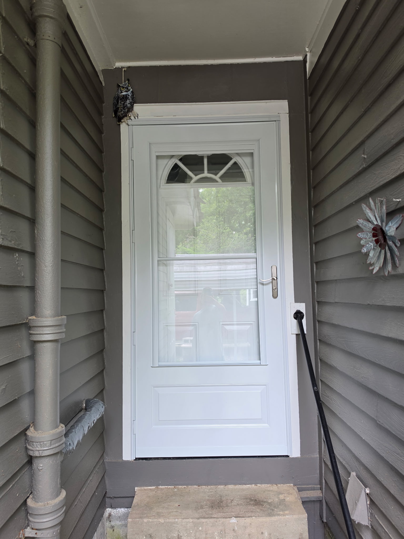 New white storm door with arched glass insert on covered front porch