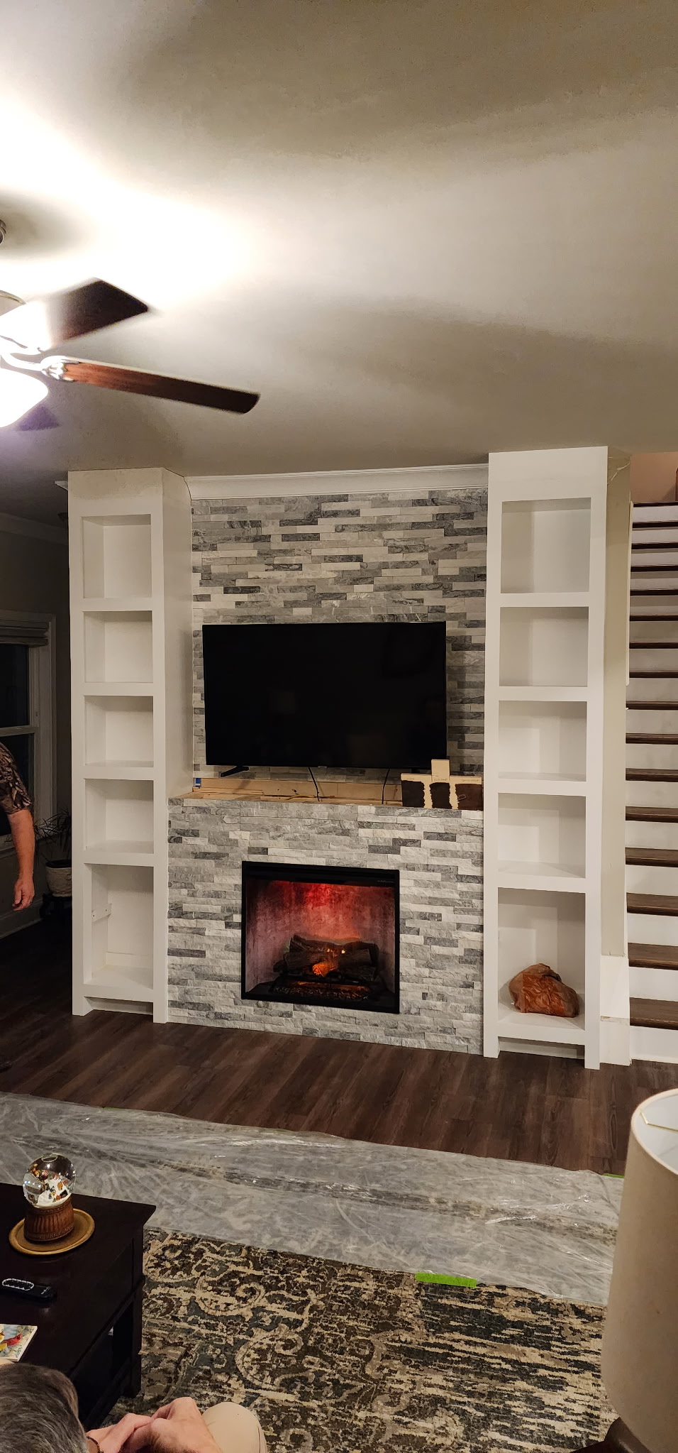 Custom fireplace surround with stone tile, built-in shelving and TV mount