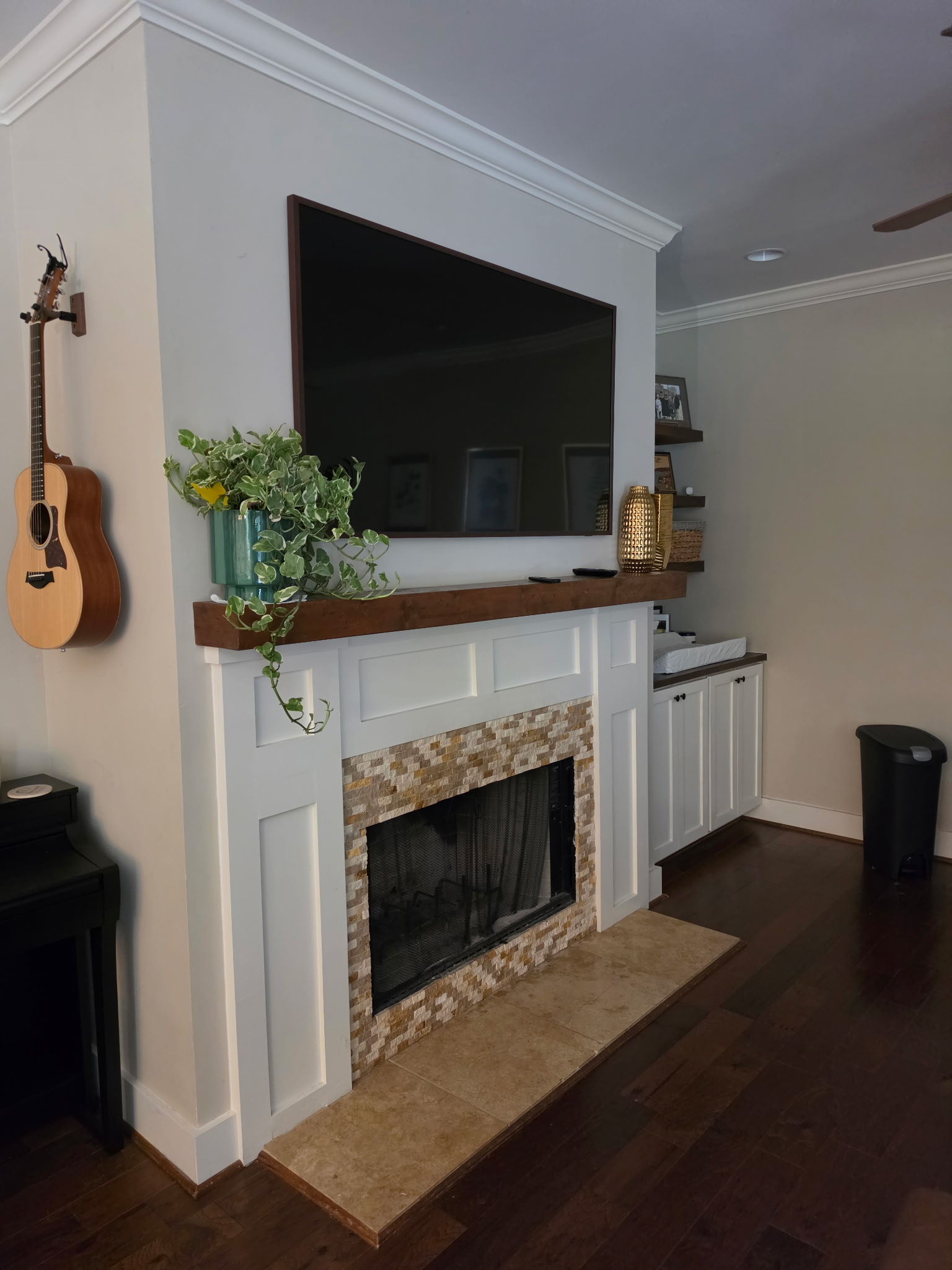 Fireplace before renovation with tan mosaic tile surround and wood mantel