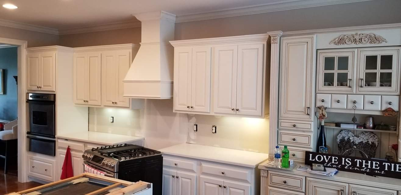 White custom kitchen cabinets with built-in range hood and black appliances