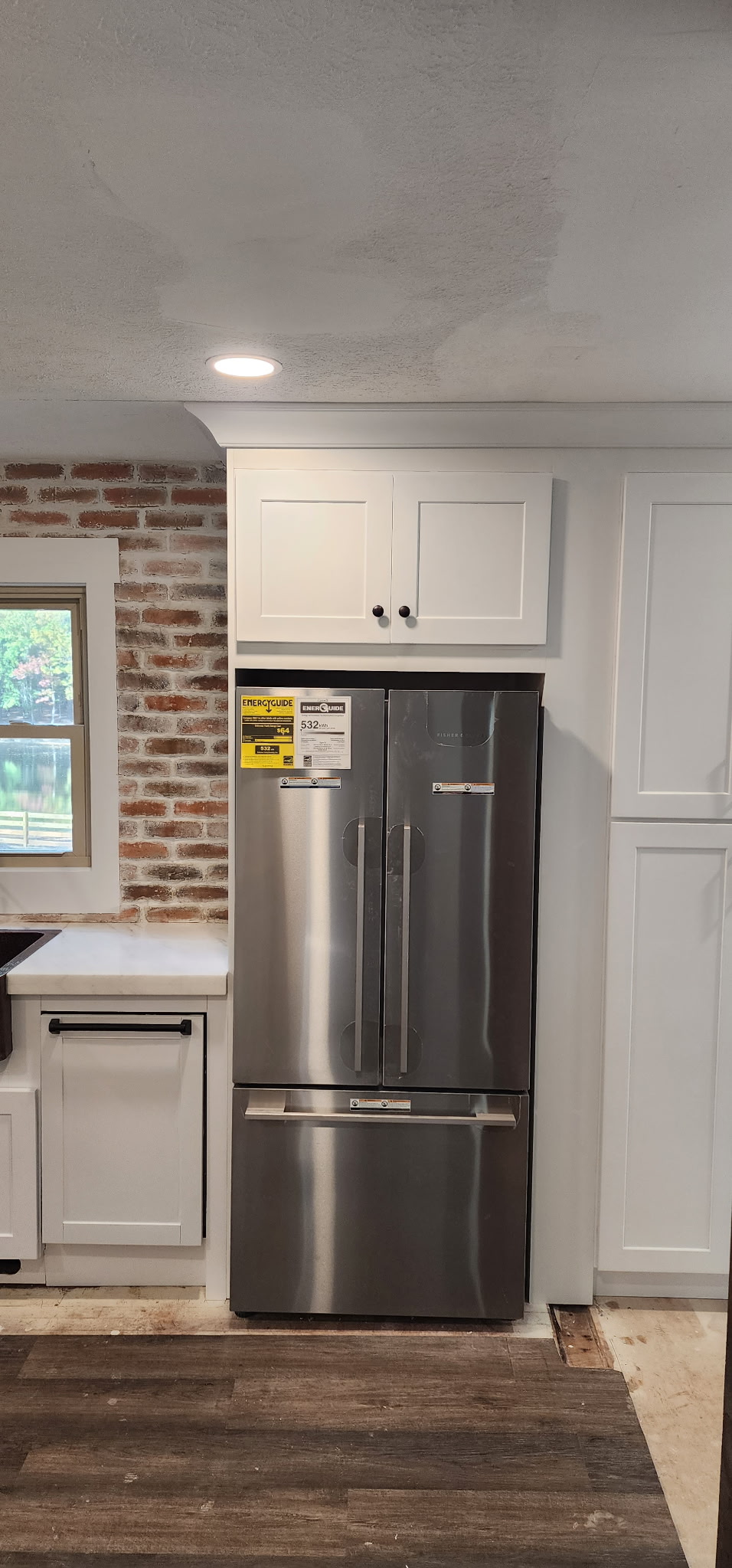 Kitchen with white shaker cabinets, exposed brick wall and stainless appliances