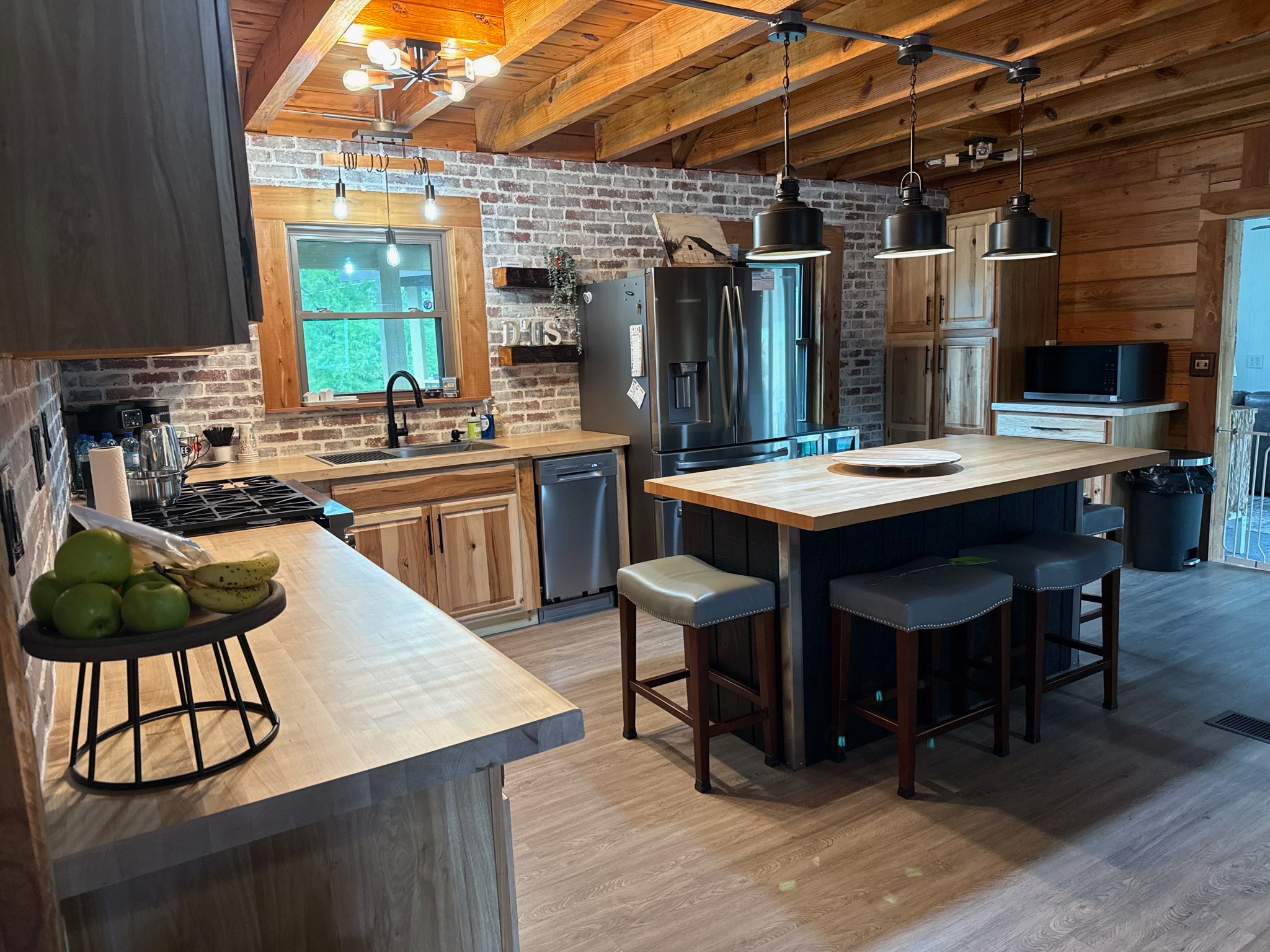 Rustic cabin kitchen with butcher block counters, brick backsplash and wood beam ceiling
