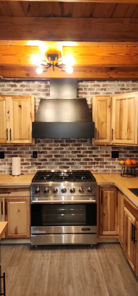 Cabin kitchen with custom range hood, brick backsplash and hickory cabinets