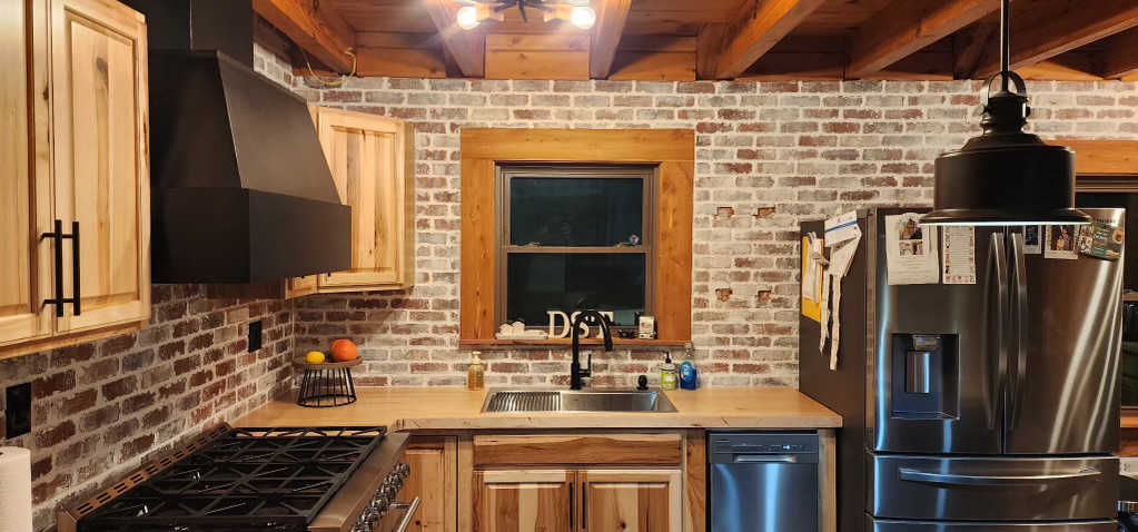 Cabin kitchen remodel with exposed brick, stainless appliances and butcher block counters